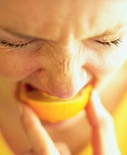 Frau beißt in Zitrone